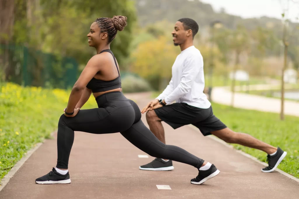 couple stretching on path in the park utc
